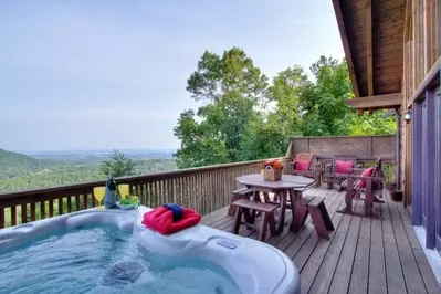 Hot tub and table on the deck of a Gatlinburg cabin with mountain views.