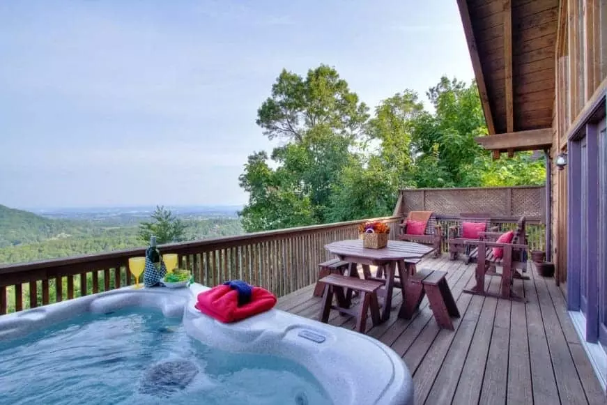 Hot tub and table on the deck of a Gatlinburg cabin with mountain views.