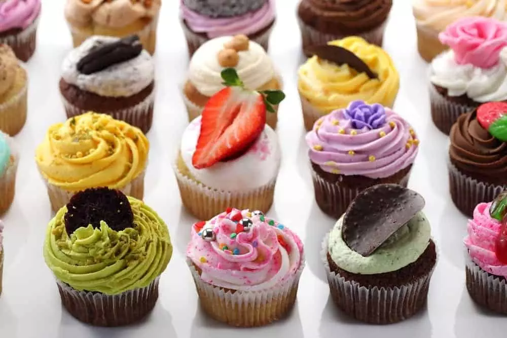 A variety of gourmet cupcakes lined up on table