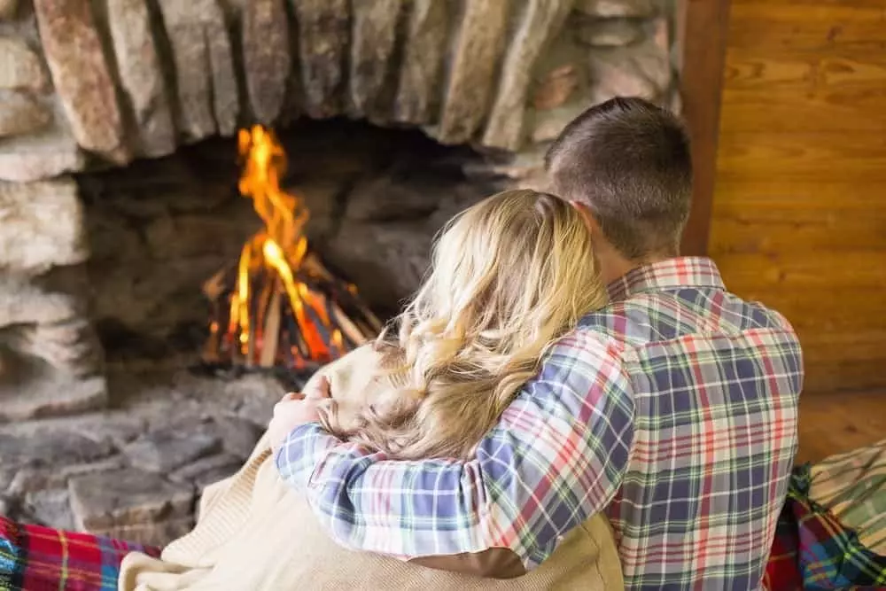Couple cuddling in front of the fireplace at one of our Gatlinburg winter cabins.