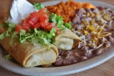 chimichanga topped with lettuce and tomatoes with rice and beans