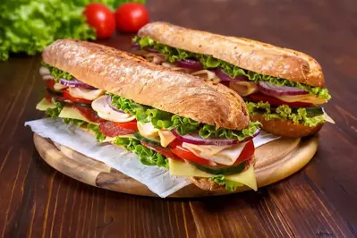 two sandwiches with cheese, tomato, turkey, lettuce