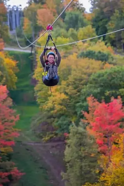 A woman ziplining in the fall.
