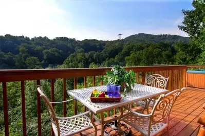 Table and chairs on the deck of a Gatlinburg cabin with mountain views.