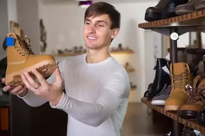 A man examining a hiking boot in a store.