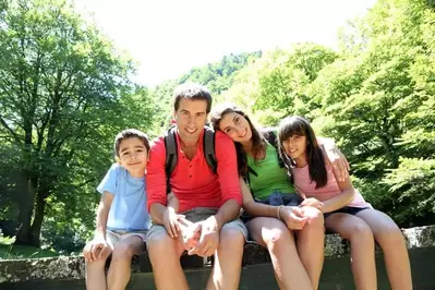 A family sitting on a bridge in the mountains.