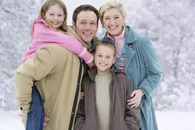 Happy family in winter coats posing for a picture in the snow.