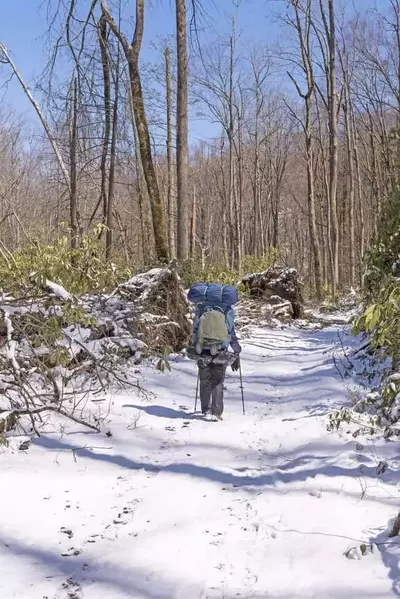 A man with a large backpack taking a winter hike in the Smoky Mountains.