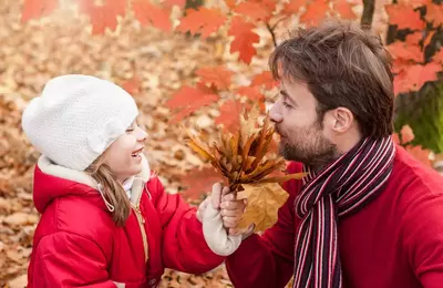 man and daughter playing in fall leaves