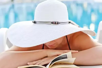 Woman reading by a pool when staying in a Pigeon Forge cabin with pool access