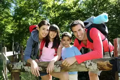 Family hiking and resting on a fence